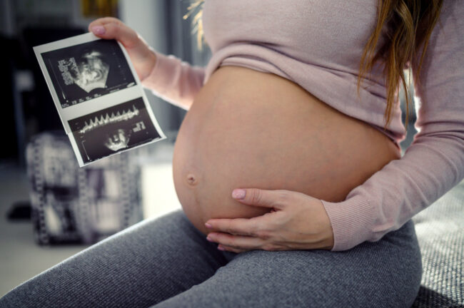 Pregnant Woman With Ultrasound Image At Home